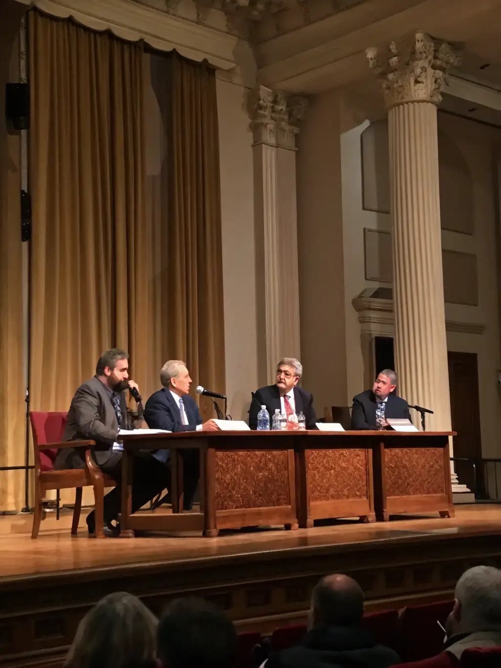 A photograph of a panel discussion at a business conference, with a moderator and several panelists seated on stage, engaging in a lively debate.